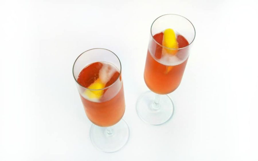 2 Sloe Royale cocktails in champagne flutes with lemon peels garnishes