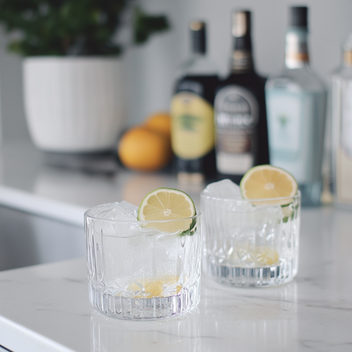 2 gin and tonics on a kitchen counter with ingredients