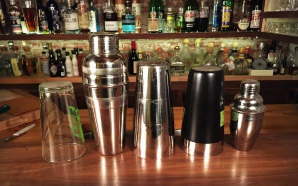 a variety of cocktail shakers varying by type and size, from metal Boston shaker to cobbler shaker to pint glass