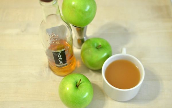 apple cocktail in a coffee mug, a hot cocktail surrounded by green apples
