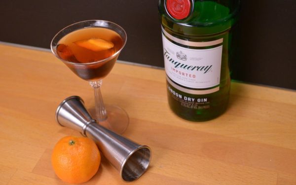 Hanky Panky cocktail in a chilled coupe glass with a cocktail jigger, bottle of gin, and an orange