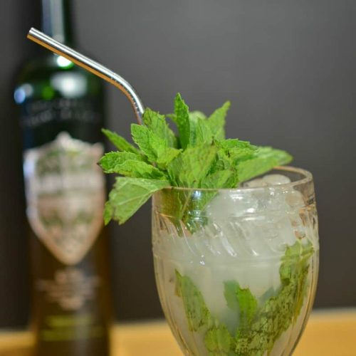 Absinthe Frappe cocktail with sprigs of mint and a metal straw