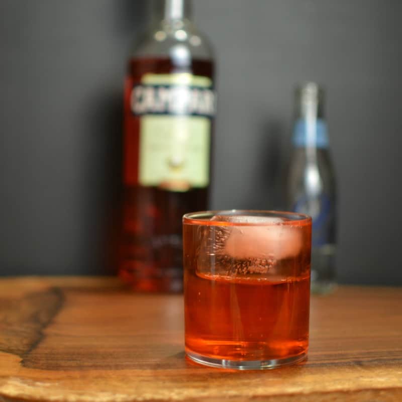 campari soda in a chilled rocks glass with a bottle of campari and soda water in the background