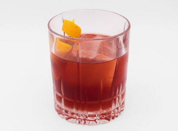 Red cocktail in an Old Fashioned. glass with lemon peel