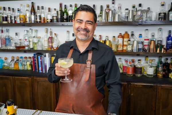 Bartender holding a sparkling cocktail with a combination of gin, brut champagne, and fresh juice