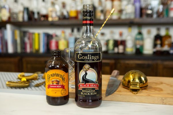 Dark rum bottle and a bottle of ginger beer on a bar
