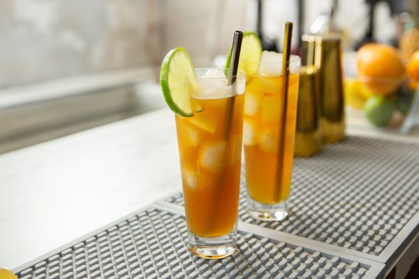 2 versions of the Dark & Stormy cocktail in highball glasses with lime wheel garnish