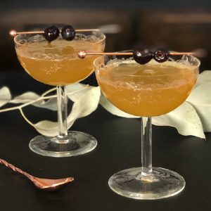 Regent's punch in chilled coupe glasses with cocktail cherries on cocktail picks