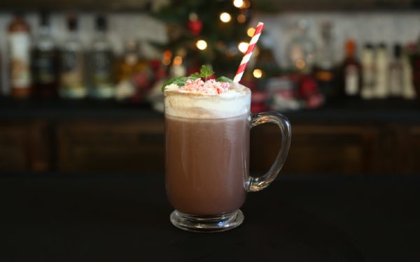 spiked hot chocolate with peppermint candy pieces and a red and white straw