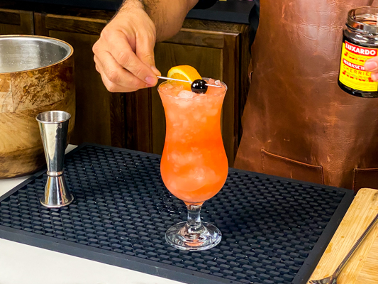 4. Putting a in a Maraschino cherry on top of a cocktail in hurricane lamp-shaped glasses