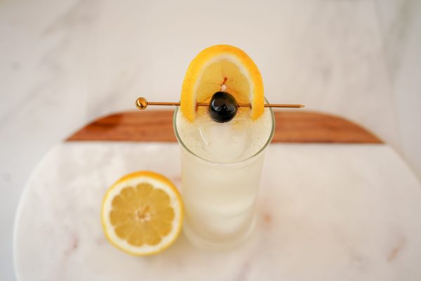 Classic garnish of cocktail cherries and piece of peel from a lemon in a tall cocktail glass