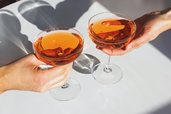 cocktails in coupe glasses being held by hands