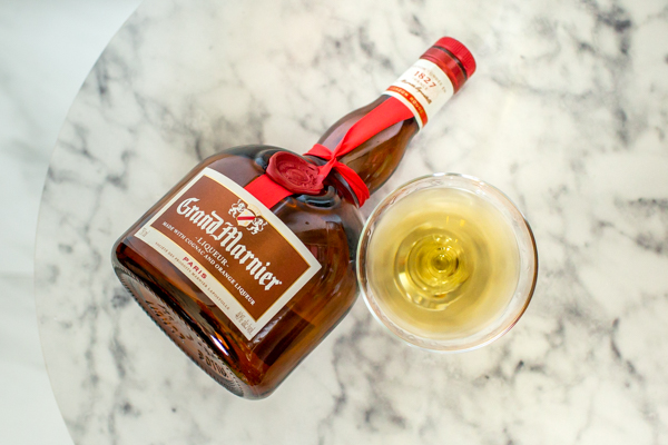 Grand Marnier orange liquor bottle next to a chilled coupe glass with orange liqueur .5 oz