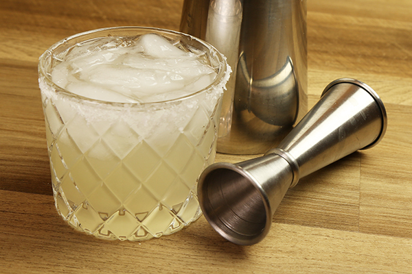 Margarita cocktail in rocks glass with cocktail shaker and alcohol jigger