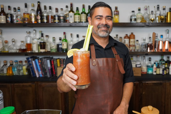 Head bartender holding a Bloody Mary cocktail with celery stalk