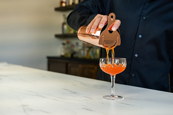 Straining a cocktail with a Hawthorne strainer in a bar