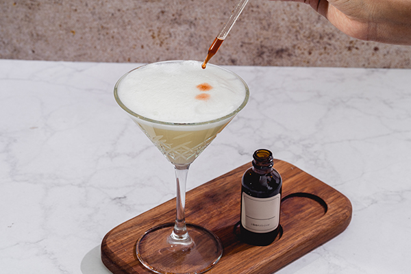 Adding bitters to a cocktail with a squeezable dropper bottles top