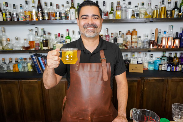 Bartender holding a warm water hot toddy with lemon slice and cloves for extra flavor