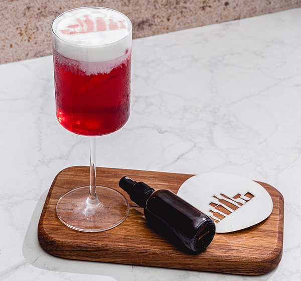 Handcrafted cocktail in a crystal cocktail glass with a stencil design that was sprayed with affordable bitters bottles or atomizer spray bottles