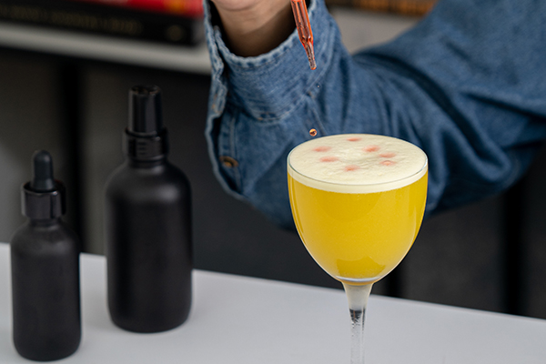professional bottles in matte black glass make for lovely bottles on a bar next to a purple cocktail