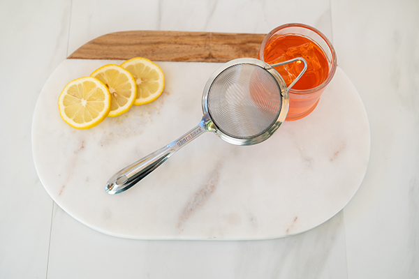mesh strainer with lemons citrus fruit and cocktail with noticeable difference in smoothness