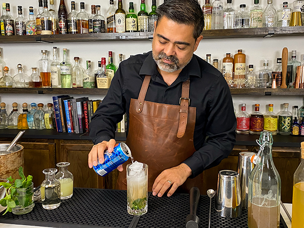 Pouring seltzer water of choice into tall glass with ice cubes before adding extra lime slices