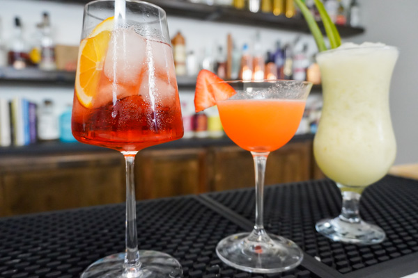summer party drinks, one in a tall glass with sugar syrup and pineapple fruit juice