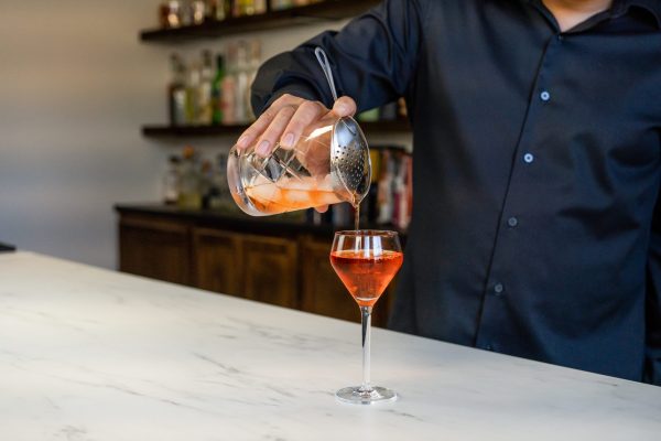pouring a cocktail from a mixing glass