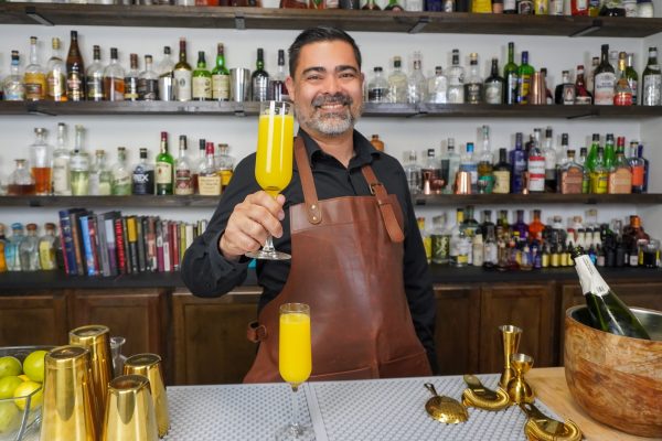 bartender holding mixed drinks mimosa with bottle of Italian prosecco for champagne cocktails on the side of the mimosa bar