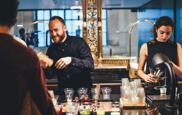 2 bartenders working at a bar, using the normal inventory and cleaning glassware