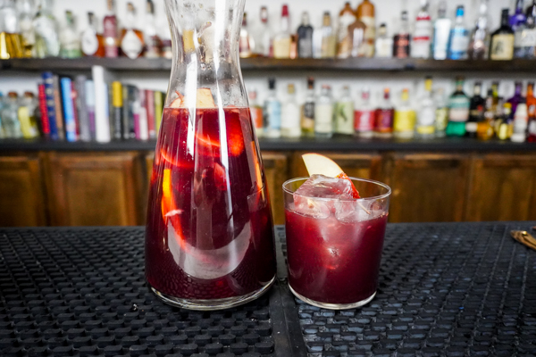a fruity beverage of sangria with fresh fruit (fresh strawberries and apples)