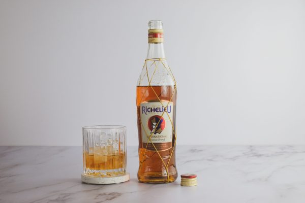 brandy for a special occasion, in a lowball glass with ice cubes next to a bottle of liquor