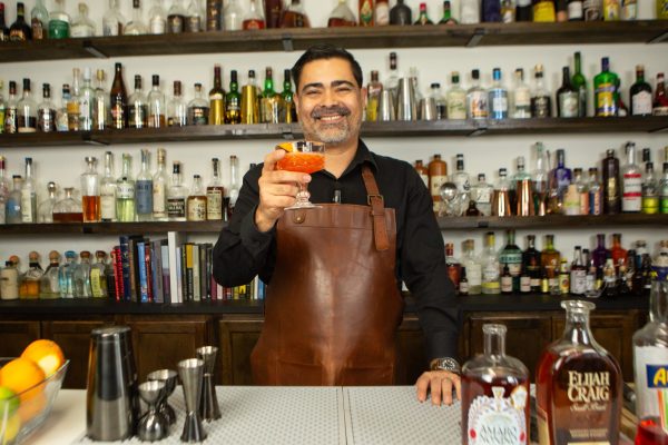 bartender holding out a cocktail in a coupe glass