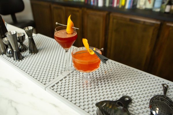 2 cocktails sitting on a bar