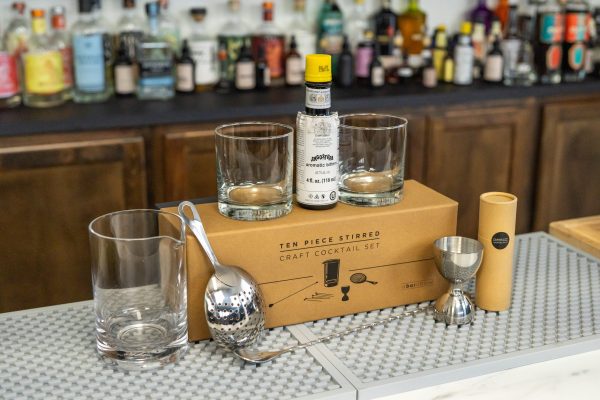 Old Fashioned gift set: 2 rocks glasses, mixing glass, strainer, jigger, spoon, cocktail picks, Angostura bitters, with box on a commercial bar