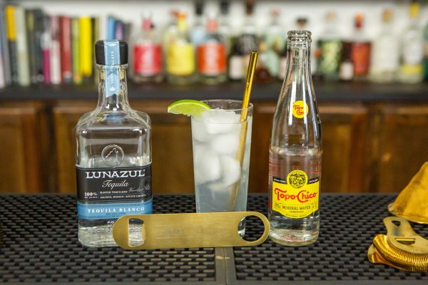 Cocktail with a bottle of tequila, bar blade bottle opener, and a bottle of Topo Chico carbonated water