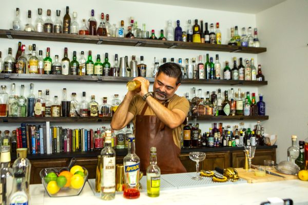 Bartender shaking cocktail ingredients with ice in a gold cocktail shaker in a bar