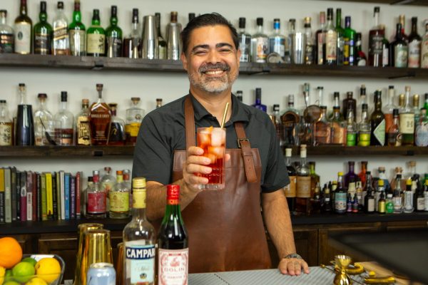 bartender holding a red cocktail in a highball glass