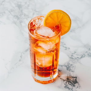 tall glass filled with Campari for a characteristic flavor, vermouth, sparkling water, and an orange twist on a white marble counter