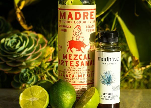 bottle of mezcal, an agave spirit, surrounded by limes