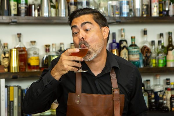 bartender drinking from a coupe, making a silly face