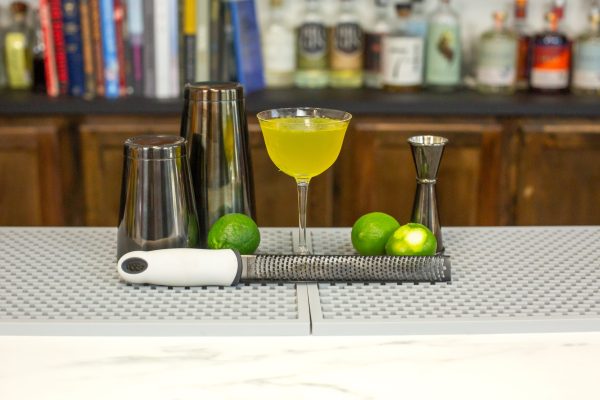 A black and white zester, an essential cooking tool, with a black colored bartender kit including a classic cocktail shaker and hawthorn strainer