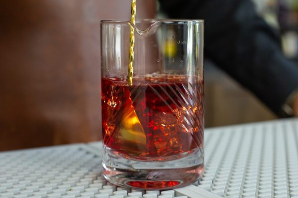 mixing glass bar tool accessory with a red cocktail in it