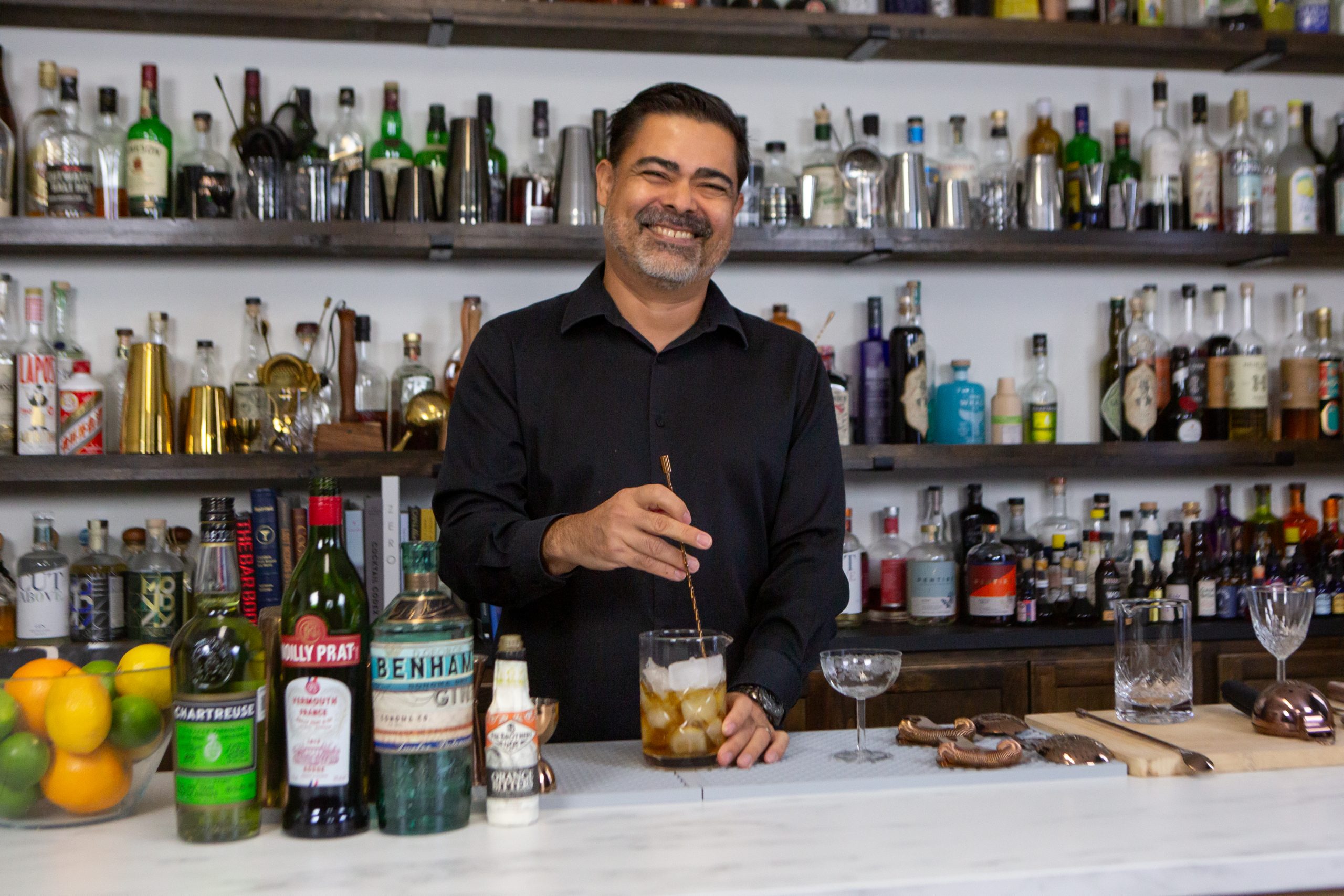 bartender stirring a cocktail ingredients with ice in a mixing glass