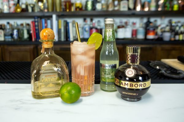 El Diablo drink in an ice-filled glass surrounded by its ingredients on a bar
