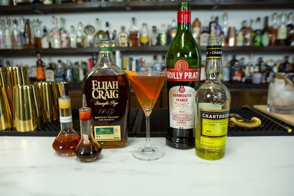 Greenpoint drink surrounded by its ingredients on a bar