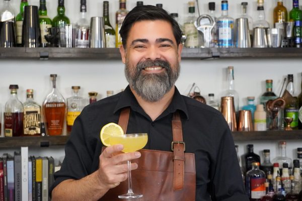 bartender smiling and holding a coupe glass in a bar