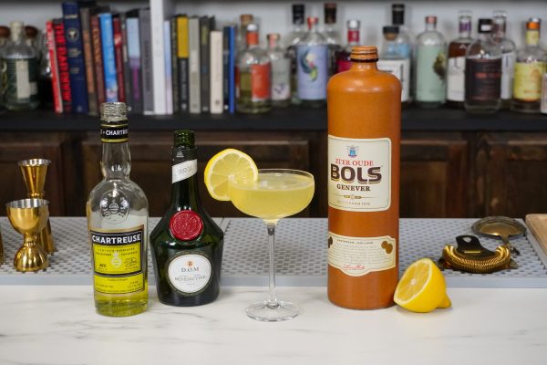 yellow mixed drink on a bar, surrounded by bottles of alcohol