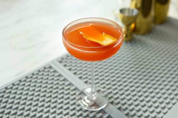 bright pink-orange drink made with a cocktail strainer