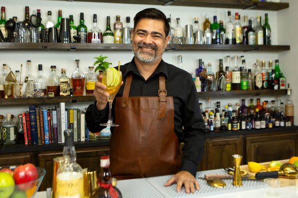 bartender holding a cocktail in a wine glass with fresh mint sprigs